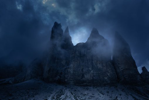Tre guglie rocciose nella nebbia con toni freddi, fotografia di paesaggio dark per il progetto The Dark Side.