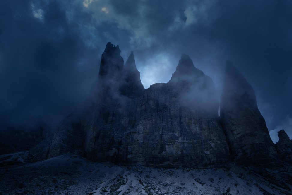 Tre guglie rocciose nella nebbia con toni freddi, fotografia di paesaggio dark per il progetto The Dark Side.