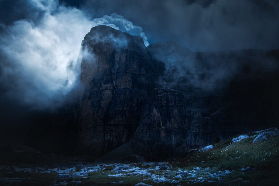 Parete rocciosa monumentale e nuvole illuminate a sinistra, fotografia di paesaggio a toni freddi per il progetto The Dark Side.